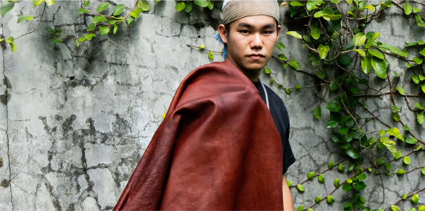 Portrait of craftsman with dyed leather draped over shoulder